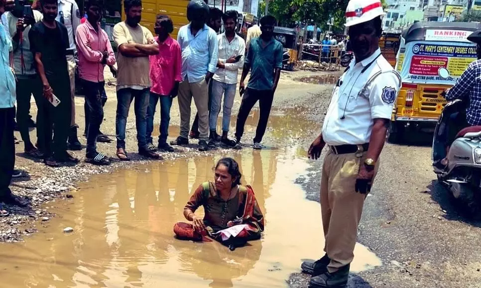 బురద గుంతలో కూర్చుని మహిళ వినూత్న నిరసన